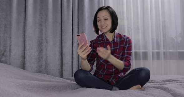 Young Woman Sit on the Bed and Enjoying Having Video Chat Using Smartphone