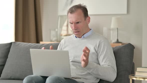 Sad Middle Aged Businessman Having Loss on Laptop on Sofa