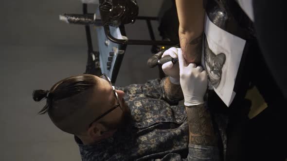 Master making tattoo on skin of client