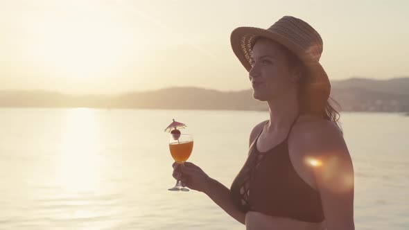 Slow Motion Video of a Girl with a Cocktail in Her Hands Walking on the Beach