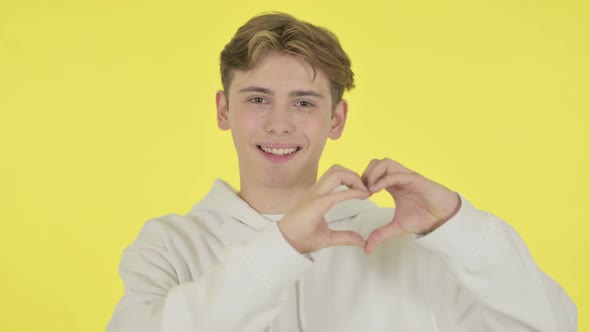 Young Man Showing Heart Shape By Hands on Yellow Background