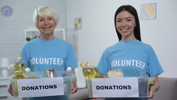 Smiling Senior and Young Volunteers Holding Food Donation Boxes Looking Camera