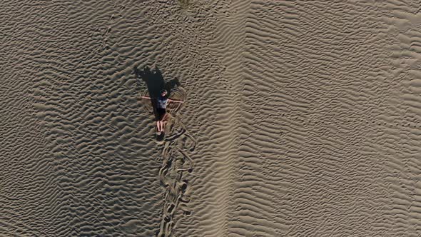 Blonde Woman is Lying on Sand and Doing a Sand Angle in Rub Al Khali Desert