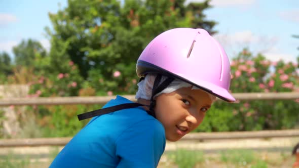 Tanned Boy in a Helmet is Riding a Chestnut Horse with a Dark Mane