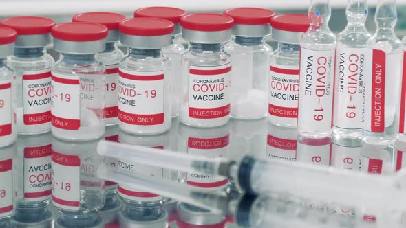 Ampoules with Vaccine and a Syringe on a Medical Table alt