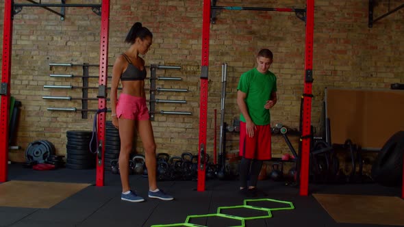 Fitness Instructor Showing Agility Ladder in and Out Drills to Female Athlete