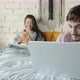 Man Freelancer Working with Laptop in Bed While Wife Using Smartphone and Smiling - VideoHive Item for Sale