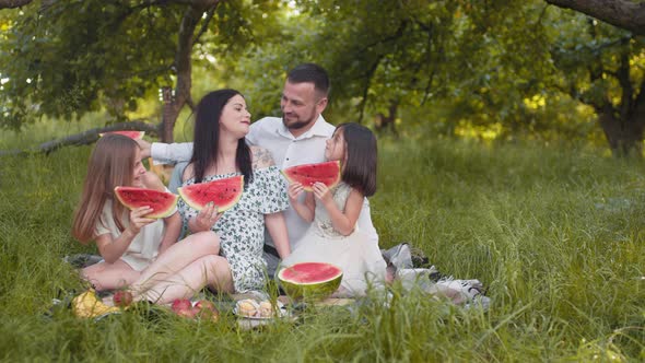 Caucasian Couple with Two Little Daughters Sitting Closely to Each Other at