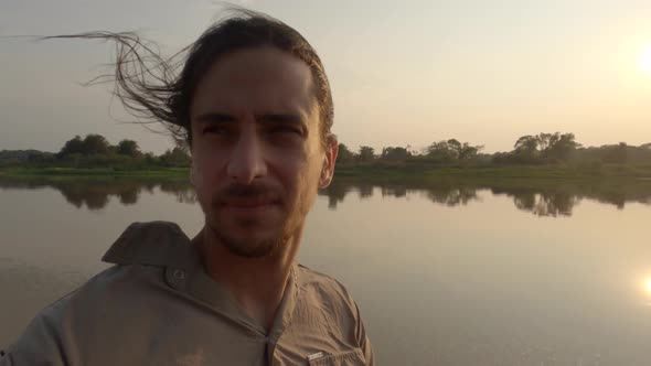 Man looking around while in boat on river with sun shining