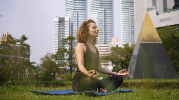 Woman Meditating In Park In City