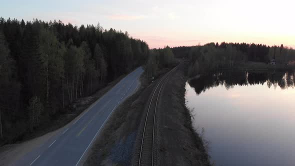 A drone view of a lonely road between a forest and the water's edge