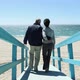 Couple walking on walkway and on beach towards the sea - VideoHive Item for Sale