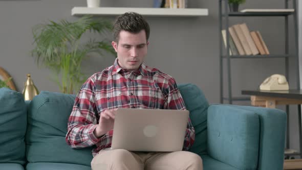 Man with Laptop Having Headache on Sofa
