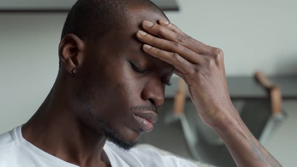 Black Man Feeling a Severe Headache From Which He Suffers Touching His Head with His Eyes Closed