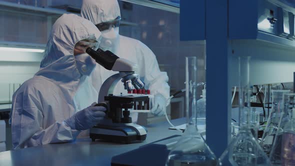 Scientists in Coveralls and Face Masks Doing Research in Lab