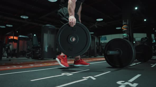 Bodybuilder Carrying Barbell Plate in Gym