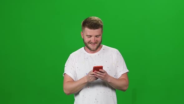 Portrait Bearded Guy Walking and Texting Message Vie Mobile Phone on Greenscreen. Chroma Key. Front