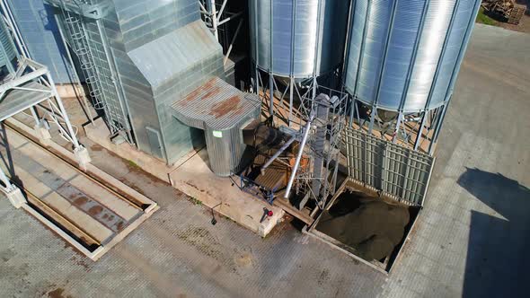 Modern metal grain elevator on field. Granary for storing and processing agricultural crop. 