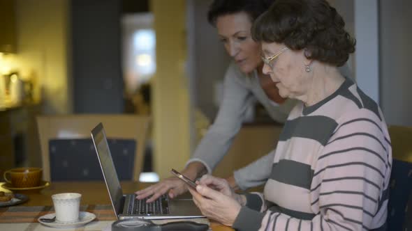 Mother and Daughter Using Phone and Laptop Together at Home