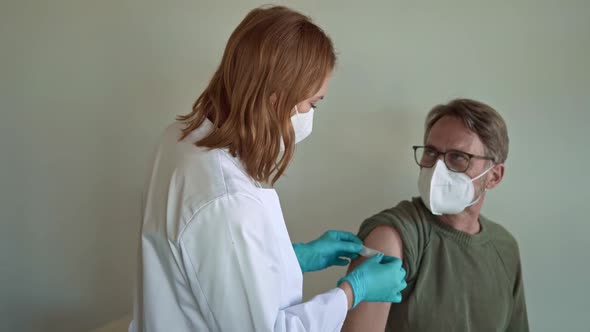 Doctor placing band aid on vaccinated patient's shoulder