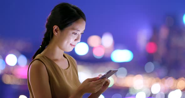 Woman look at mobile phone in city at night