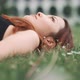A young woman lying on the grass looking at the sky and moving her head - VideoHive Item for Sale