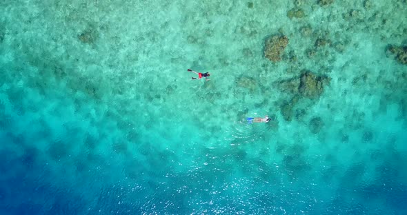 Wide drone tourism shot of a white paradise beach and blue ocean background in 4K