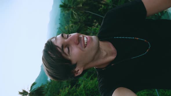 Vertical Video Portrait of Smiling Young Man Tourist Making a Selfie or Video Call on Green Jungle