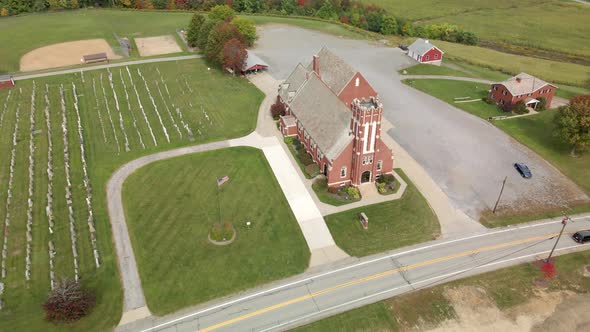 A reverse aerial establishing shot of a typical red brick church in the Pennsylvania countryside in