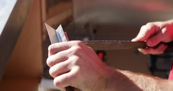 Close up shot of the hands of a construction worker using a large rough metal file to grind and smoo