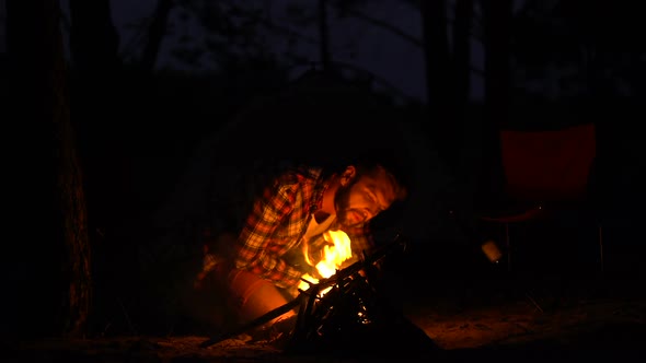 Bearded Male Making Fire for Friends Group, Blowing on Flames, Active Weekend