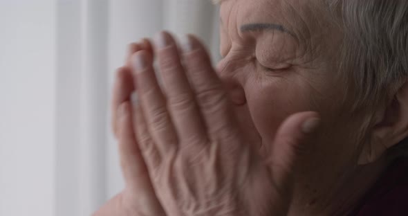 Old woman crying covering her face with her hands. Depression and despair in an older female.