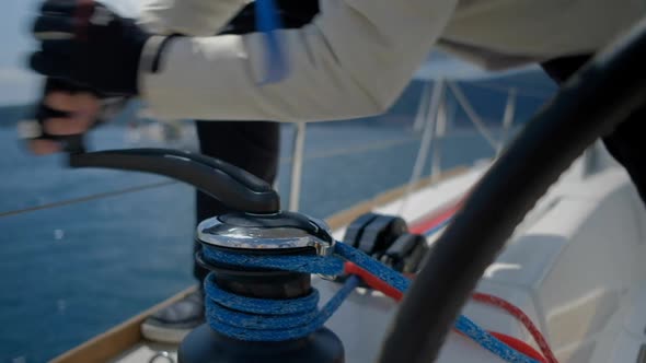 Closeup up of Yachtsman hands pulling rope  on sailboat, yacht detail, working on water transport