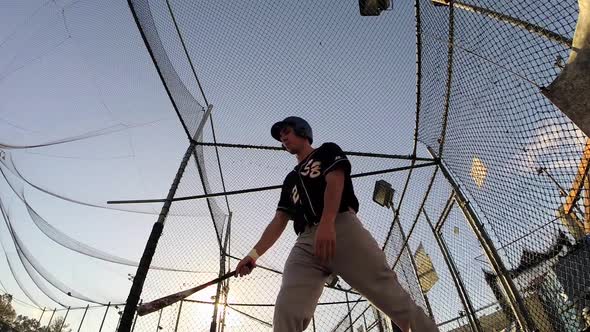 A baseball player practicing at the batting cages.