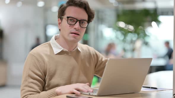 Man with Laptop Showing Thumbs Down Sign