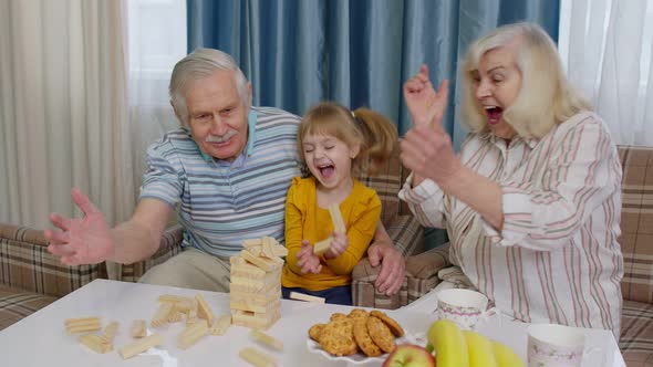 Excited Child Girl Kid Involved in Build Blocks Board Game with Senior Grandmother and Grandfather
