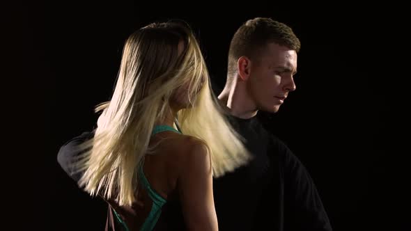 Couple of Ballroom Dancers Perform Bachata Dance Element on Black Studio Background in Darkness