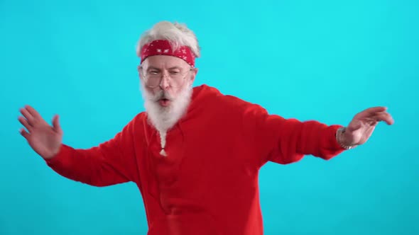 Adult Grayhaired Hipster in a Red Hoodie Dancing to the Music on a Blue Background a Cheerful Man is