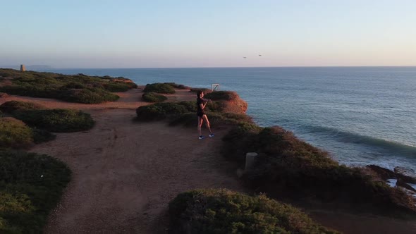 Sportswoman stretching legs on seashore at sunset