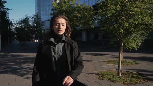 Attractive Woman in a Business Suit and with a Bag Runs Down the City Street