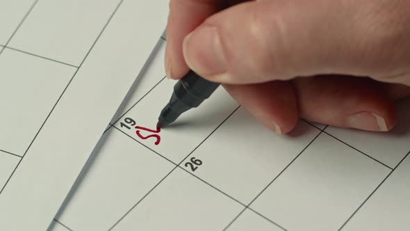 Close Up of Female Hand Writing Reminder to START DIET with Red Marker on Paper Calendar