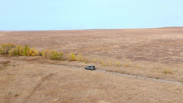 Offroad Car Driving on Country Road Along Yellowed Fields in Village. Drone Aerial View SUV Vechie