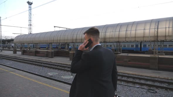 Successful Businessman Walking Through Railway Station and Talking on Phone