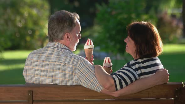 Senior Couple Eating Ice Cream Sitting Bench Park