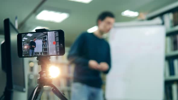 Instructor Waving To Remote Learners on Smartphone Screen Blurred Background