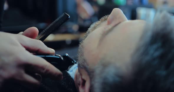 Man is Cut His Beard with a Hair Clipper in a Hair Salon