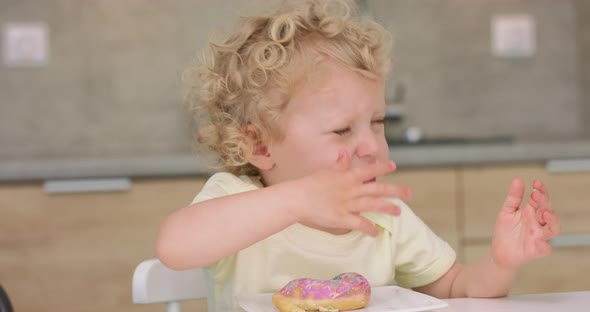 Adorable Little Girl Licks Her Fingers After Eating a Donut While Sitting at the Kitchen Table Donut