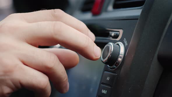 The Fingers of a Man Press Buttons on the Car Radio. Music on the Go