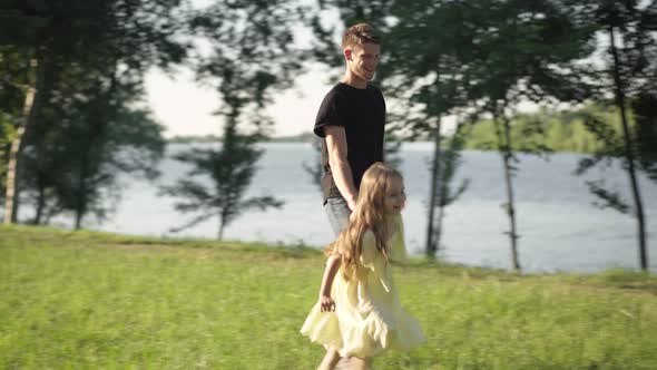 Wide Shot Joyful Girl Running in Sunny Park Holding Hand of Young Man