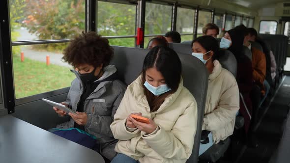 Multiracial Teens in Face Masks Riding School Bus